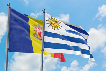 Uruguay and Andorra flags waving in the wind against white cloudy blue sky together. Diplomacy concept, international relations.