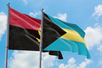 Bahamas and Angola flags waving in the wind against white cloudy blue sky together. Diplomacy concept, international relations.