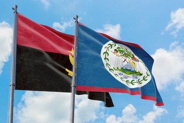 Belize and Angola flags waving in the wind against white cloudy blue sky together. Diplomacy...