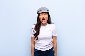 young latin pretty woman shouting aggressively, looking very angry, frustrated, outraged or...