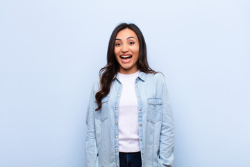 young latin pretty woman looking happy and pleasantly surprised, excited with a fascinated and...
