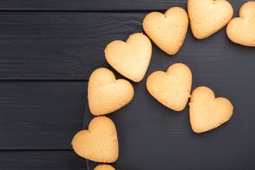 Heart shaped cookies decorated for Valentine's Day. Round frame with heart shaped cookies on a black wooden table