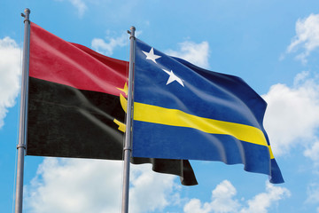 Curacao and Angola flags waving in the wind against white cloudy blue sky together. Diplomacy...