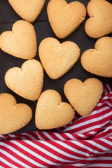 Heart shaped cookies decorated for Valentine's Day. Free space for text. Wooden plate with heart shaped cookies on a black wooden table