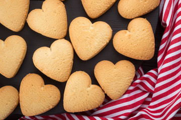 Heart shaped cookies decorated for Valentine's Day. Free space for text. Wooden plate with heart shaped cookies on a black wooden table