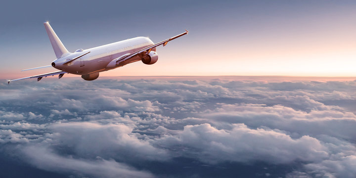 Commercial airplane jetliner flying above dramatic clouds in beautiful light. Travel concept.