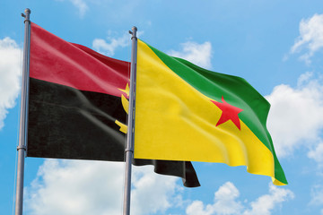 French Guiana and Angola flags waving in the wind against white cloudy blue sky together. Diplomacy concept, international relations.