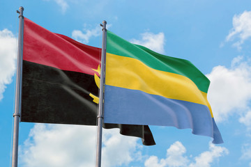Gabon and Angola flags waving in the wind against white cloudy blue sky together. Diplomacy concept, international relations.