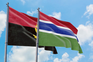 Gambia and Angola flags waving in the wind against white cloudy blue sky together. Diplomacy concept, international relations.