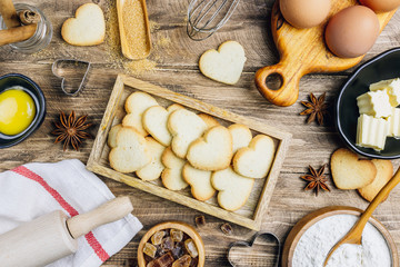 Valentine's Day baking culinary background. Ingredients for cooking on wooden kitchen table, baking recipe for pastry. Heart shape cookies.