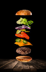 Tasty hamburger with flying ingredients on dark background. High resolution image.