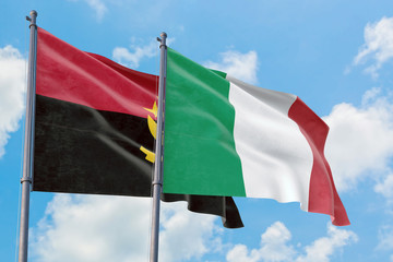 Italy and Angola flags waving in the wind against white cloudy blue sky together. Diplomacy concept, international relations.