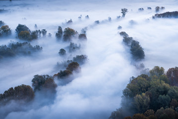 Abstract with Airuno on Adda river in Italy at sunrise with myst fog trees foliage in autumn fall season