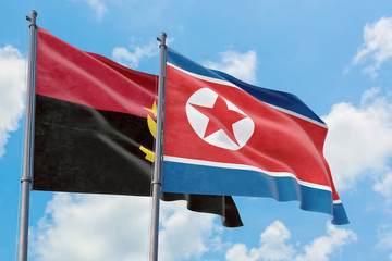 North Korea and Angola flags waving in the wind against white cloudy blue sky together. Diplomacy concept, international relations.