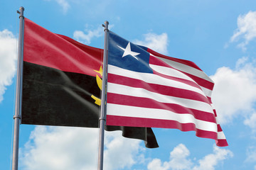 Liberia and Angola flags waving in the wind against white cloudy blue sky together. Diplomacy...