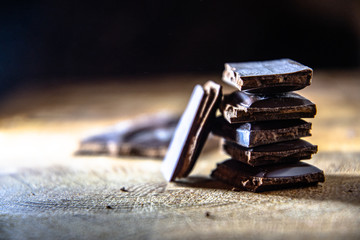 Black chocolate with truffle filling on a kitchen wooden board.