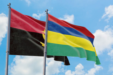 Mauritius and Angola flags waving in the wind against white cloudy blue sky together. Diplomacy concept, international relations.