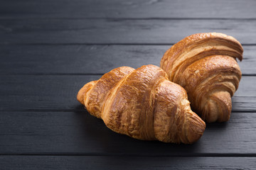 Croissants on a black wooden table. Croissant breakfast. Croissants on a wooden board and a black wooden table. Fresh French Baked Croissants. Warm Fresh Buttery Rolls. Free space for text.