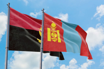 Mongolia and Angola flags waving in the wind against white cloudy blue sky together. Diplomacy...