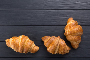 Croissants on a black wooden table. Croissant breakfast. Croissants on a wooden board and a black wooden table. Fresh French Baked Croissants. Warm Fresh Buttery Rolls. Free space for text. View from 