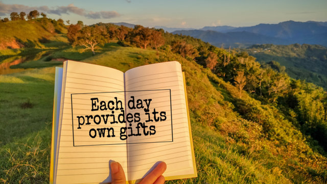 inspirational and motivational quote of each day provides its own gifts written on book with sunset background