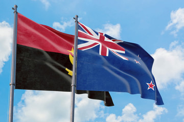 New Zealand and Angola flags waving in the wind against white cloudy blue sky together. Diplomacy...