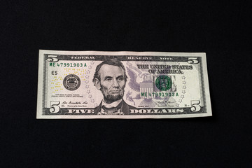 On the black background is one bill in size five dollars.