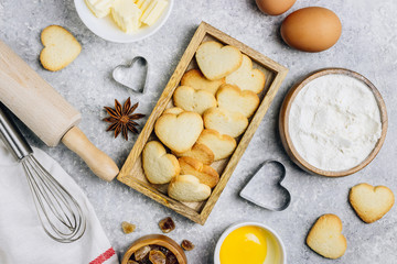 Valentine's Day baking culinary background. Ingredients for cooking on wooden kitchen table, baking recipe for pastry. Heart shape cookies.