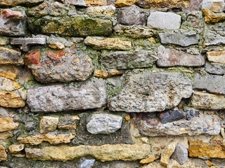 Old stone wall of colored stones close-up background texture