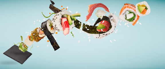 Pieces of delicious japanese sushi frozen in the air on pastel color background.