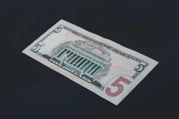 The American five dollars lie on the back on a black background.