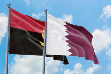 Qatar and Angola flags waving in the wind against white cloudy blue sky together. Diplomacy...