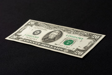 One twenty dollar bill isolated on a black background.