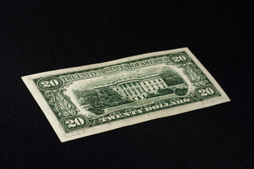 Close up of twenty dollars lie on the back on a black background.