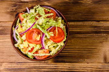 Vegan salad with savoy cabbage, tomatoes and onion in a ceramic bowl. Top view