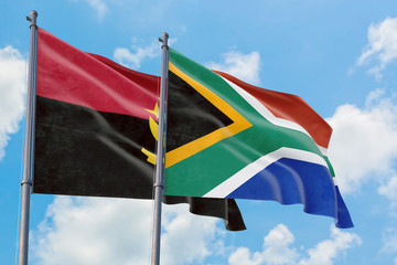 South Africa and Angola flags waving in the wind against white cloudy blue sky together. Diplomacy concept, international relations.