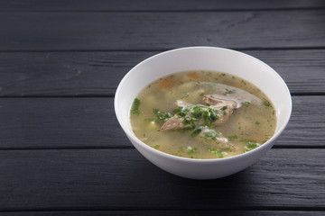 Bowl of chicken soup with bread. Chicken soup in a white plate on a black wooden table. Chicken noodle. bakso, meatball soup with noodles. Free space for text. 