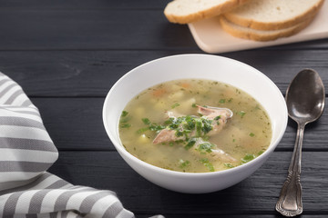 Bowl of chicken soup with bread. Chicken soup in a white plate on a black wooden table. Chicken noodle. bakso, meatball soup with noodles. Free space for text. 