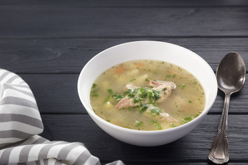Bowl of chicken soup with bread. Chicken soup in a white plate on a black wooden table. Chicken noodle. bakso, meatball soup with noodles. Free space for text. 
