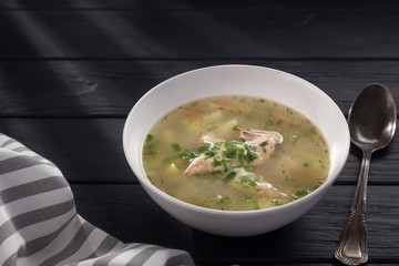 Bowl of chicken soup with bread. Chicken soup in a white plate on a black wooden table. Chicken noodle. bakso, meatball soup with noodles. Free space for text. 