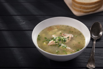 Bowl of chicken soup with bread. Chicken soup in a white plate on a black wooden table. Chicken noodle. bakso, meatball soup with noodles. Free space for text. 