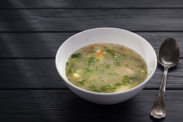 Bowl of chicken soup with bread. Chicken soup in a white plate on a black wooden table. Chicken noodle. bakso, meatball soup with noodles. Free space for text. 