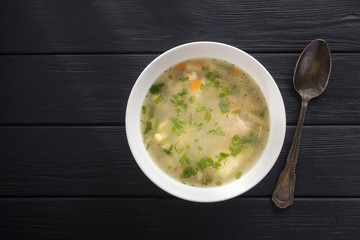 Bowl of chicken soup. Chicken soup in a white plate on a black wooden table. Chicken noodle. bakso, meatball soup with noodles. Free space for text. View from above. Top view. 