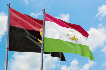 Tajikistan and Angola flags waving in the wind against white cloudy blue sky together. Diplomacy concept, international relations.