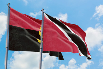 Trinidad And Tobago and Angola flags waving in the wind against white cloudy blue sky together....