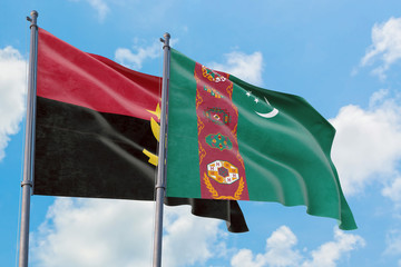 Turkmenistan and Angola flags waving in the wind against white cloudy blue sky together. Diplomacy...