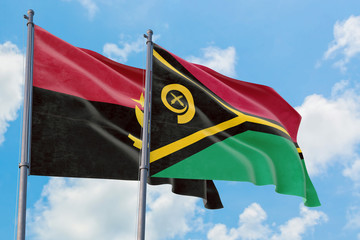 Vanuatu and Angola flags waving in the wind against white cloudy blue sky together. Diplomacy concept, international relations.