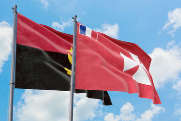 Wallis And Futuna and Angola flags waving in the wind against white cloudy blue sky together....