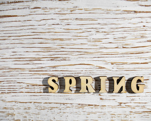 The word Spring in wooden letters on a wooden old background.