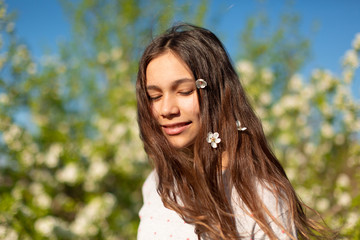 Naklejka premium Portrait of a young beautiful teenager girl in a blooming spring green garden